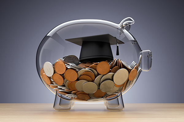 Glass piggy bank filled with coins and a graduation cap